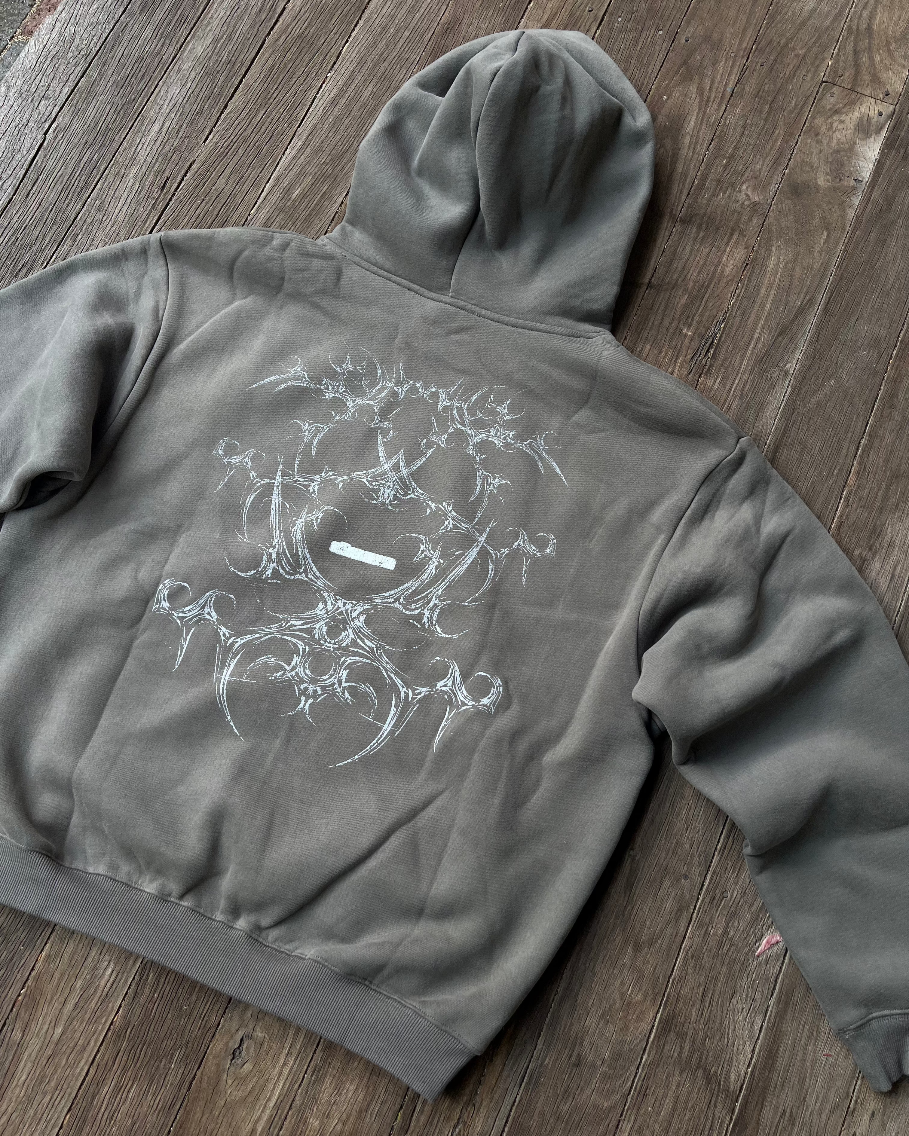 Gray hoodie with a white graphic design on a wooden floor