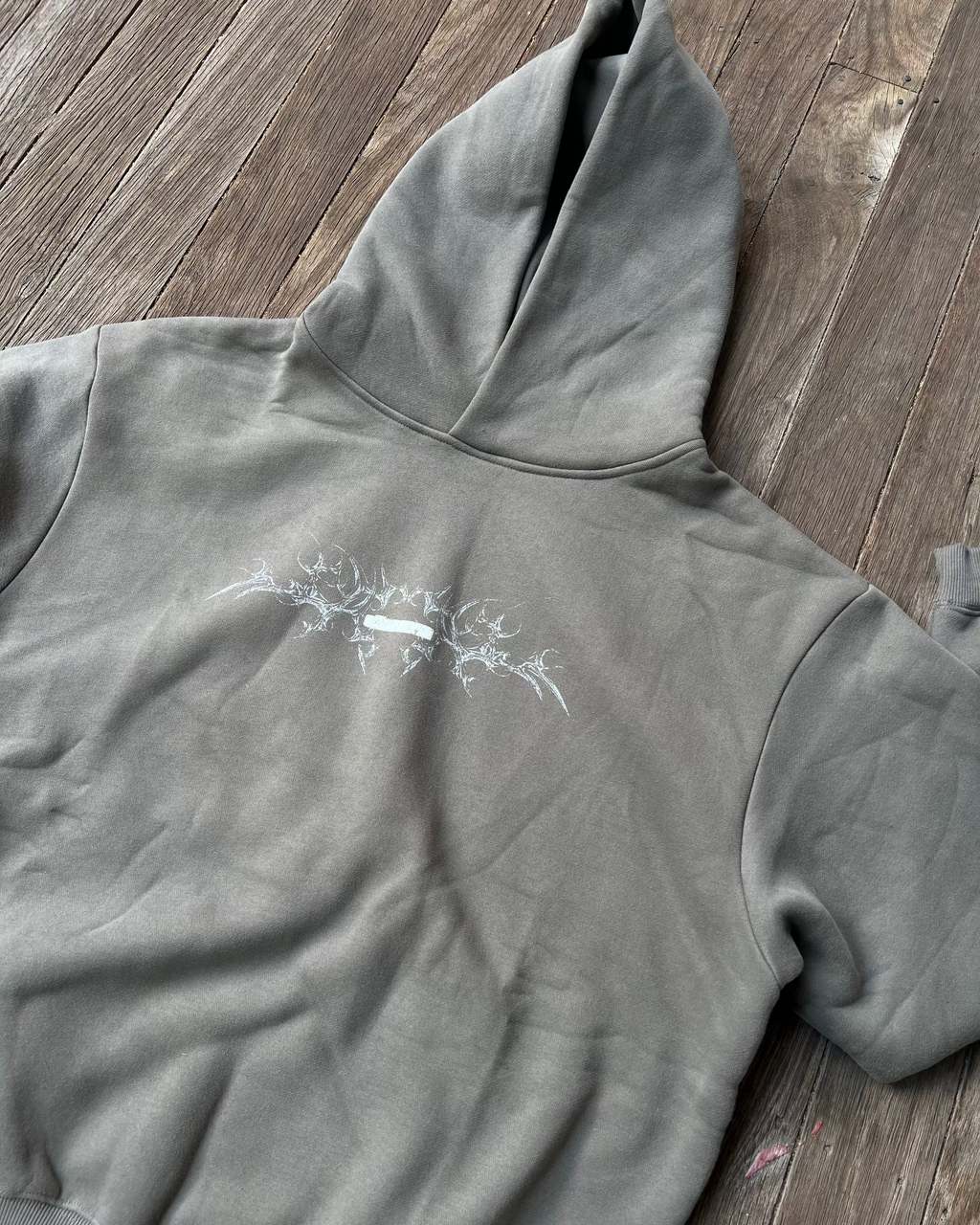 Gray hoodie with a white graphic on a wooden surface